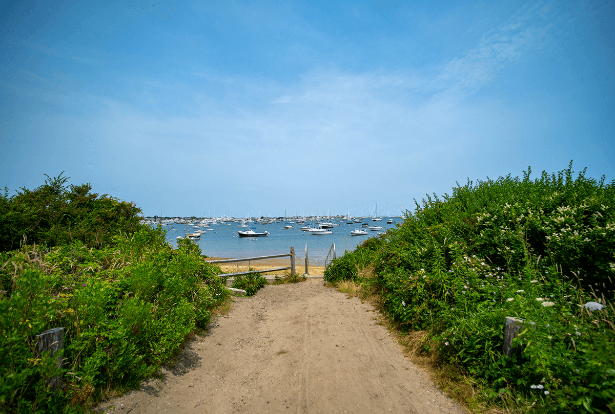 Sandy path opening onto a Nantucket harbor full of boats